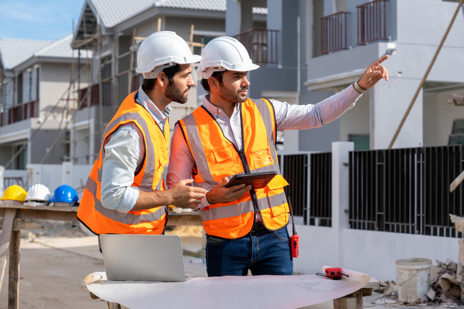 Deux gestionnaires de chantier en discussion devant un bâtiment en construction
